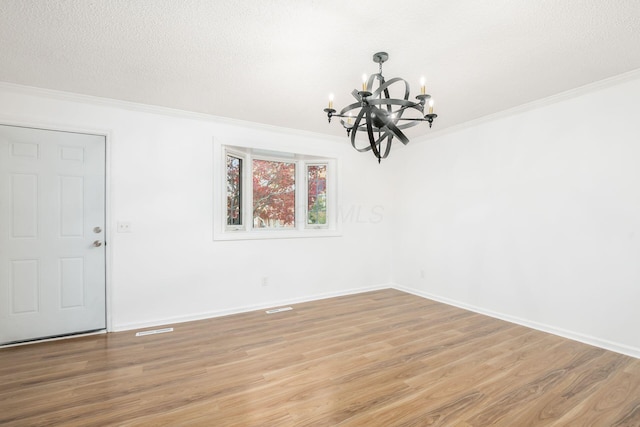 unfurnished room with hardwood / wood-style flooring, crown molding, a textured ceiling, and an inviting chandelier