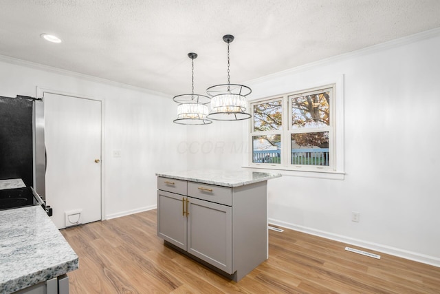 kitchen featuring stainless steel refrigerator, hanging light fixtures, light hardwood / wood-style floors, gray cabinets, and a kitchen island