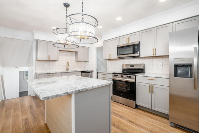 kitchen with gray cabinetry, stainless steel appliances, a chandelier, a kitchen island, and light wood-type flooring