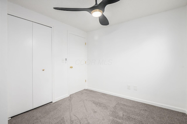 unfurnished bedroom featuring carpet floors, a closet, and ceiling fan