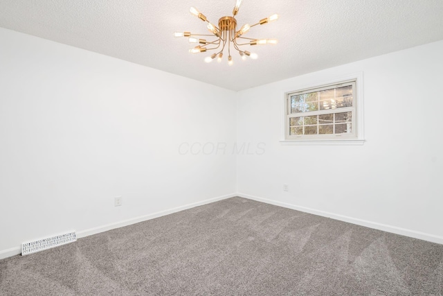 spare room with carpet, a textured ceiling, and an inviting chandelier