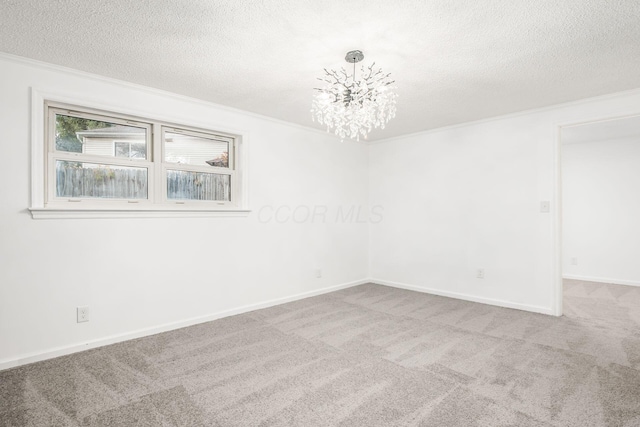 carpeted empty room with ornamental molding, a textured ceiling, and an inviting chandelier