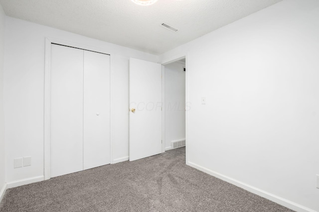 unfurnished bedroom featuring carpet floors, a textured ceiling, and a closet