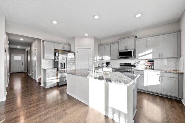 kitchen featuring gray cabinetry, dark hardwood / wood-style floors, stainless steel appliances, and an island with sink