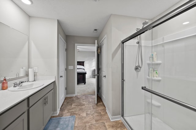 bathroom with a shower with door, vanity, and a textured ceiling