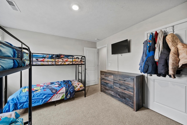 bedroom with light carpet and a textured ceiling