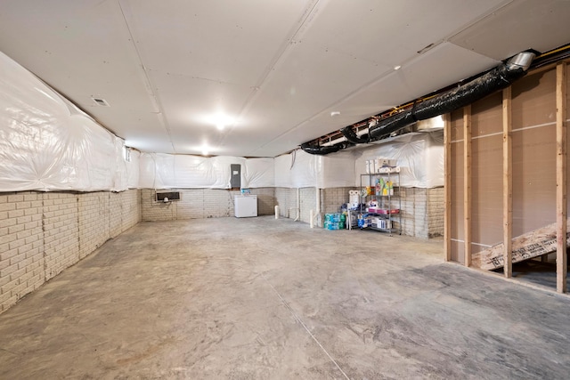 basement with electric panel and brick wall