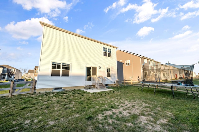 rear view of house featuring a trampoline, cooling unit, and a lawn