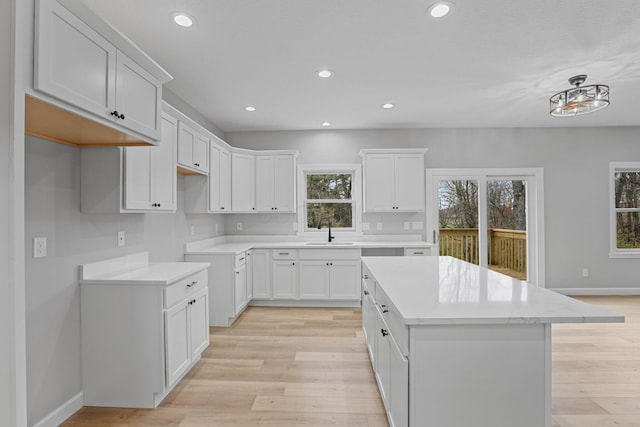 kitchen featuring a kitchen island, light wood-type flooring, a sink, and recessed lighting