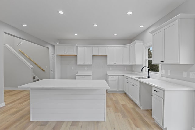 kitchen with a center island, recessed lighting, light wood-style floors, white cabinetry, and a sink