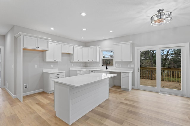 kitchen with recessed lighting, a kitchen island, white cabinetry, baseboards, and light wood-type flooring