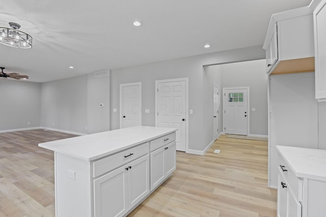 kitchen featuring light wood finished floors, white cabinetry, light countertops, and recessed lighting