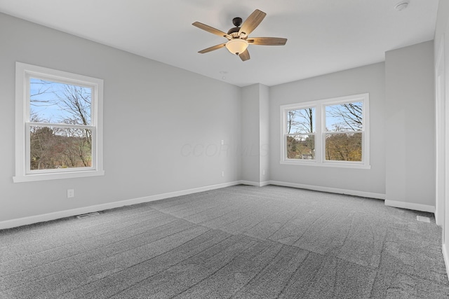 carpeted empty room with a ceiling fan and baseboards