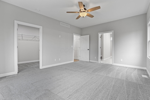 unfurnished bedroom featuring carpet floors, visible vents, a spacious closet, and baseboards