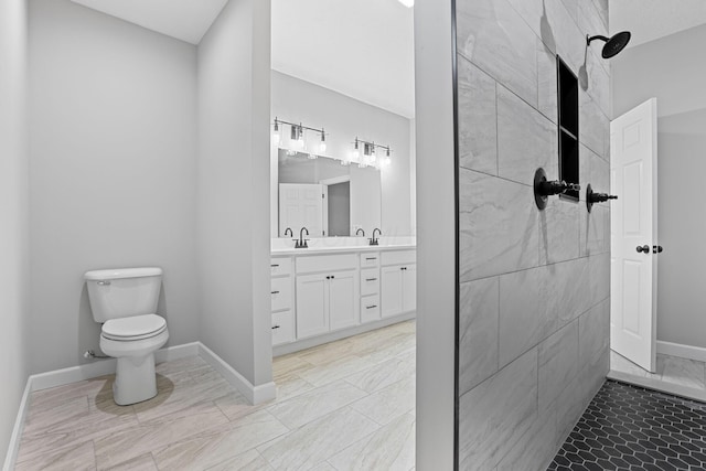 full bath featuring toilet, a tile shower, vanity, and baseboards