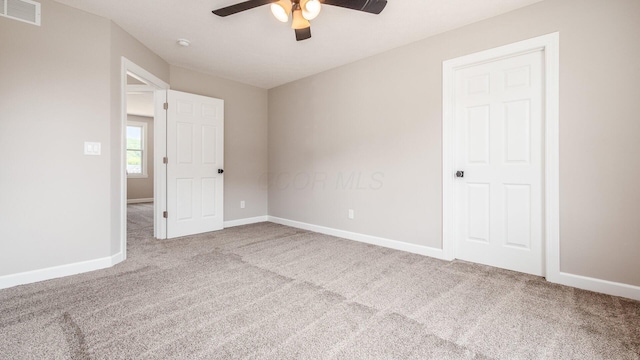 empty room featuring a ceiling fan, carpet flooring, visible vents, and baseboards