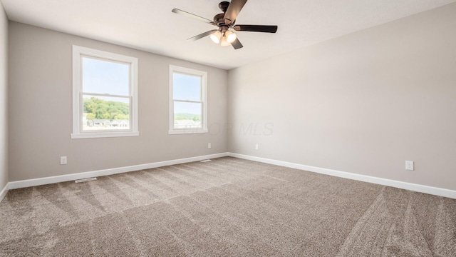 carpeted spare room with a ceiling fan and baseboards