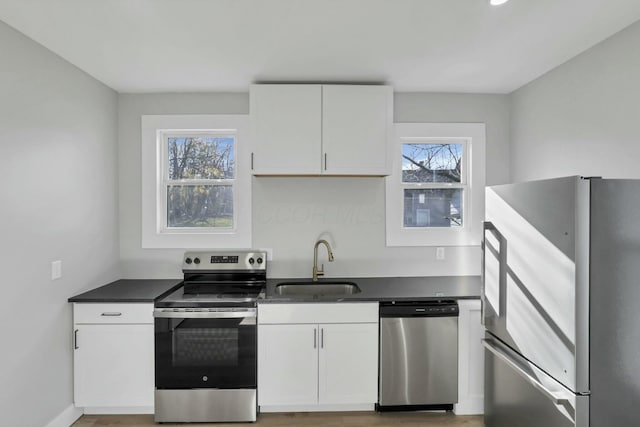 kitchen featuring white cabinets, stainless steel appliances, a healthy amount of sunlight, and sink