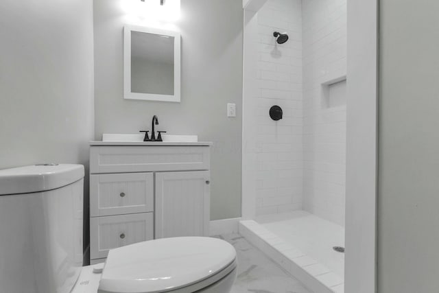 bathroom featuring vanity, toilet, and a tile shower