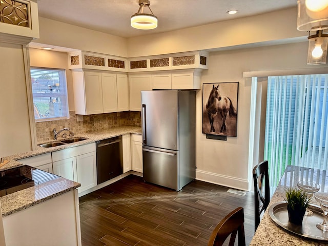 kitchen featuring appliances with stainless steel finishes, light stone counters, white cabinetry, and sink