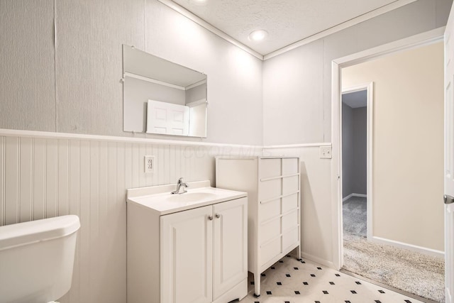 bathroom with a textured ceiling, vanity, toilet, and crown molding