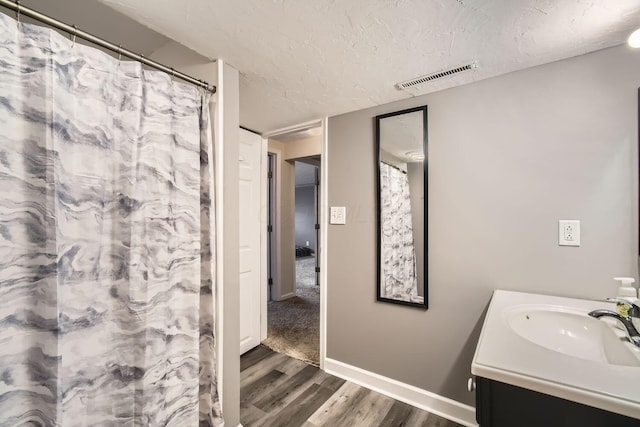 bathroom with a shower with curtain, vanity, wood-type flooring, and a textured ceiling