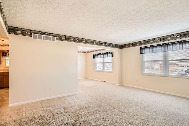 carpeted spare room with a textured ceiling