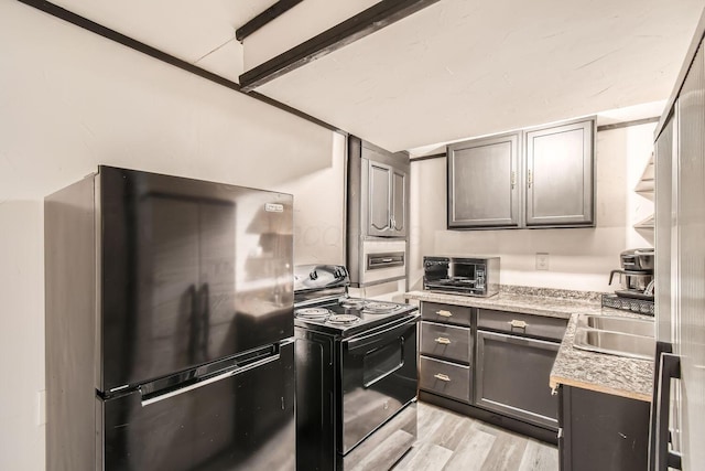 kitchen with black range with electric cooktop, light hardwood / wood-style flooring, fridge, and sink