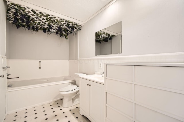 bathroom featuring a bathtub, vanity, toilet, ornamental molding, and a textured ceiling