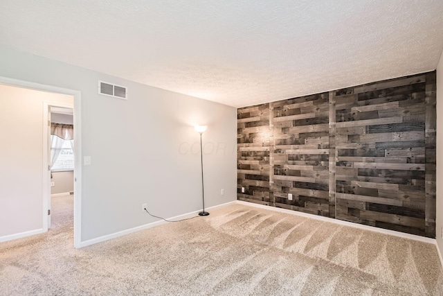 carpeted empty room featuring wood walls and a textured ceiling