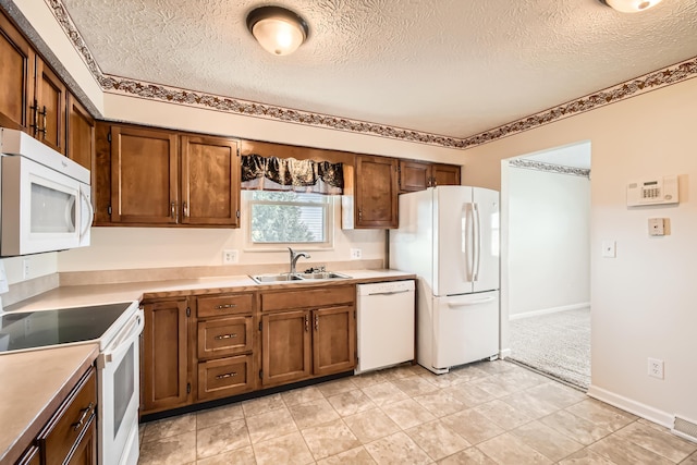 kitchen with a textured ceiling, light colored carpet, white appliances, and sink