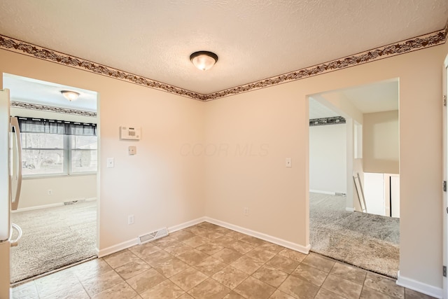 empty room with carpet and a textured ceiling