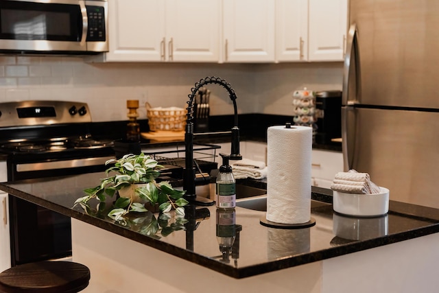 kitchen featuring white cabinets, dark stone countertops, and appliances with stainless steel finishes