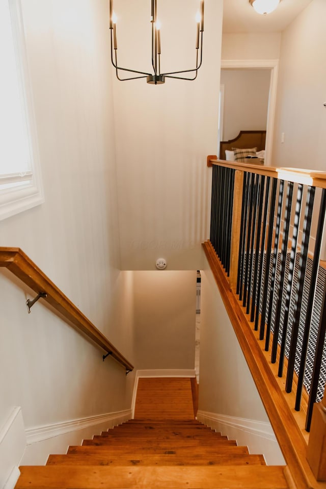 staircase featuring hardwood / wood-style floors and an inviting chandelier