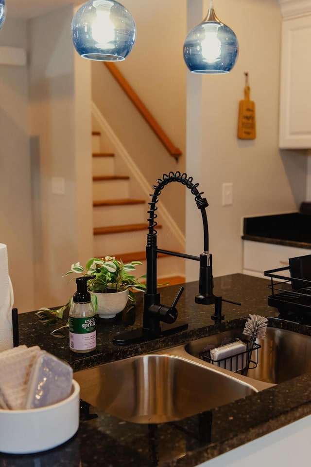 interior space featuring white cabinets, pendant lighting, sink, and dark stone countertops