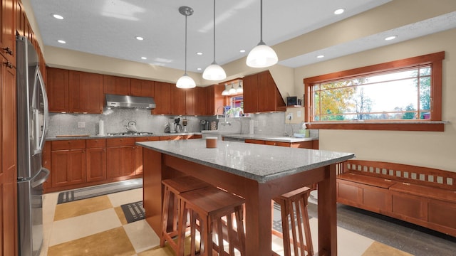 kitchen featuring decorative light fixtures, tasteful backsplash, light stone counters, and stainless steel appliances