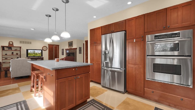 kitchen featuring a kitchen breakfast bar, a center island, decorative light fixtures, and appliances with stainless steel finishes