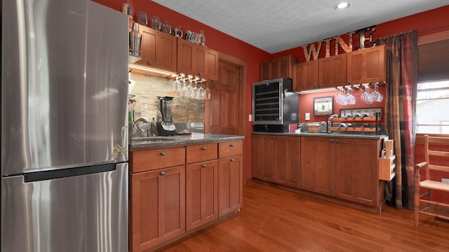 kitchen with stainless steel refrigerator, sink, beverage cooler, light hardwood / wood-style floors, and a textured ceiling