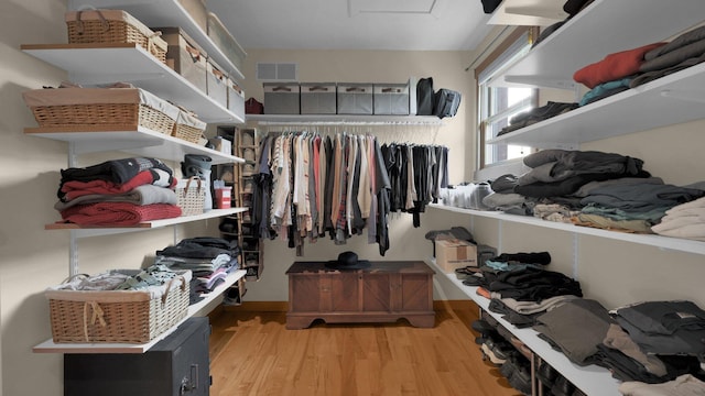 walk in closet with light hardwood / wood-style floors