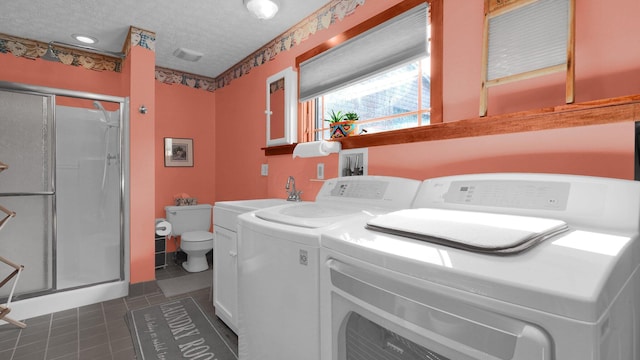 washroom with a textured ceiling, dark tile patterned flooring, and independent washer and dryer