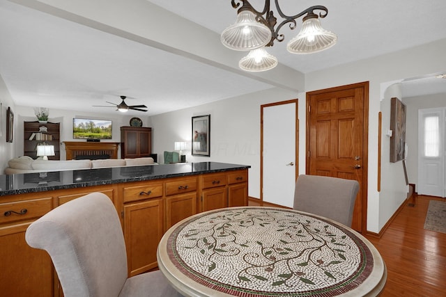 kitchen with a ceiling fan, wood finished floors, open floor plan, brown cabinetry, and baseboards