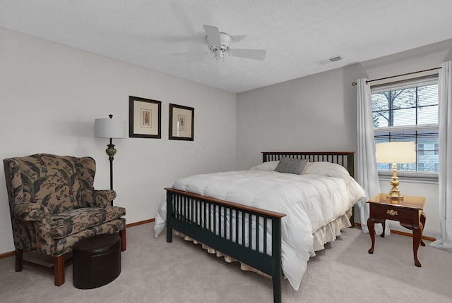 bedroom featuring a textured ceiling, ceiling fan, visible vents, and light carpet