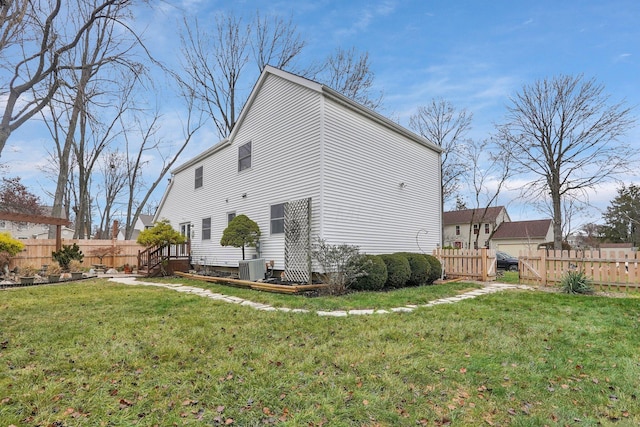 back of property with a lawn, fence, and central air condition unit