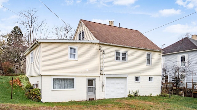 rear view of property with a yard and a garage