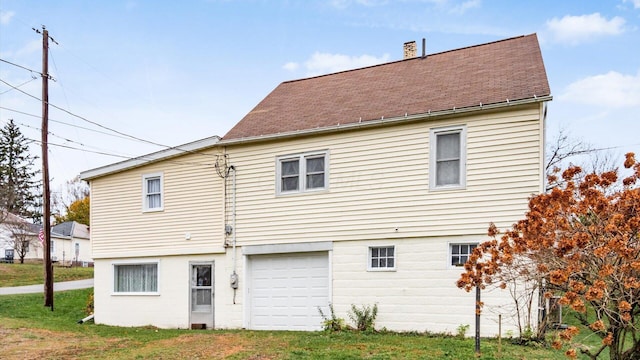 rear view of house with a lawn and a garage