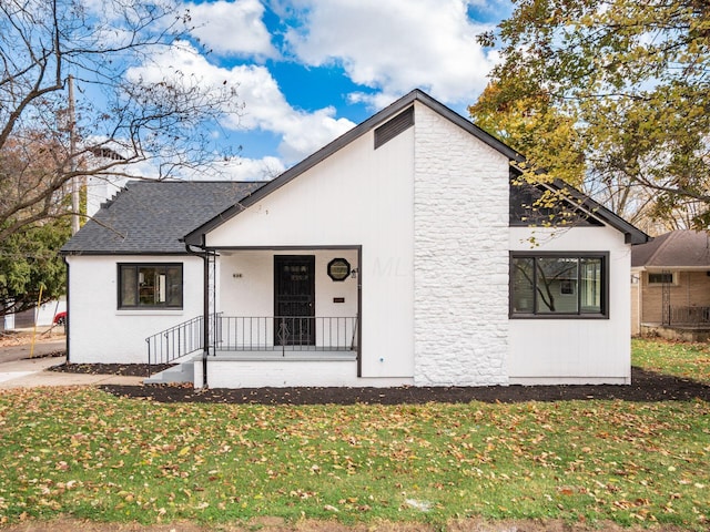 back of house featuring a lawn and covered porch