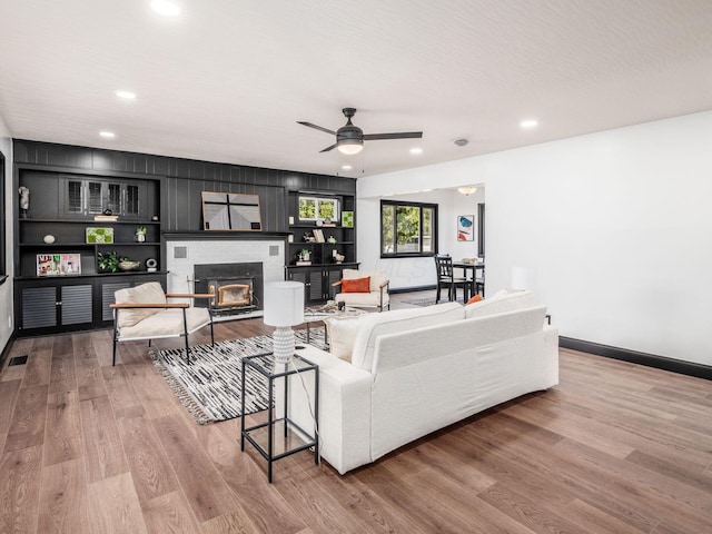 living room featuring hardwood / wood-style floors, ceiling fan, and a brick fireplace