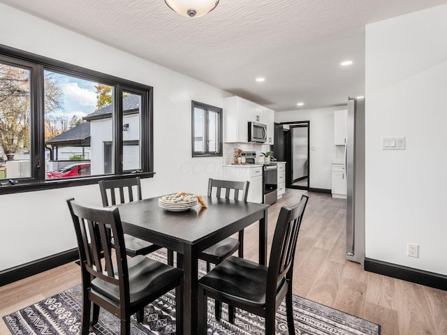 dining area featuring light hardwood / wood-style flooring and a textured ceiling