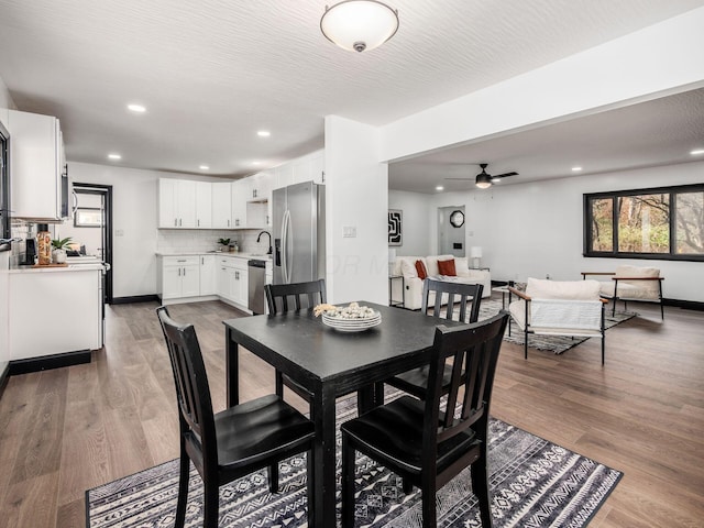 dining area with hardwood / wood-style flooring, ceiling fan, sink, and a textured ceiling