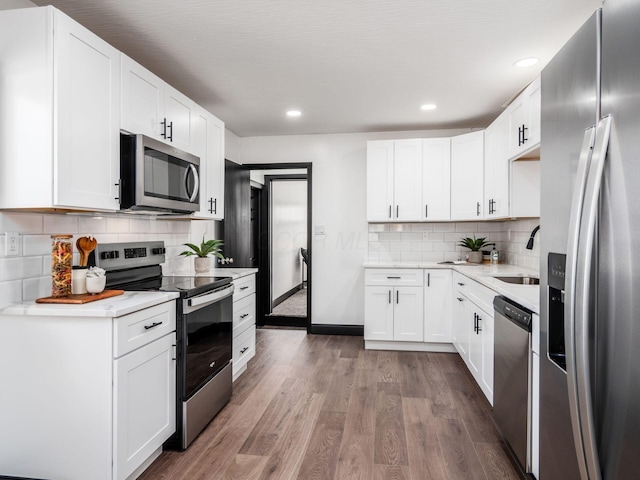 kitchen featuring white cabinets, sink, dark hardwood / wood-style floors, appliances with stainless steel finishes, and tasteful backsplash